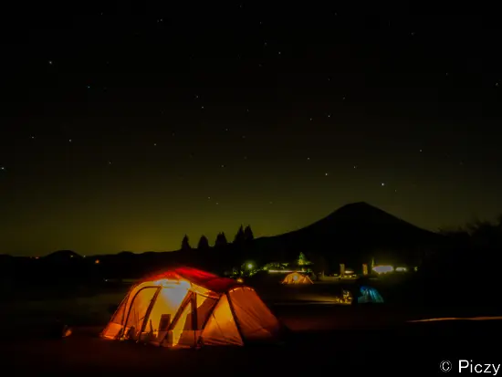 夜のキャンプ場の灯りと富士山のシルエット